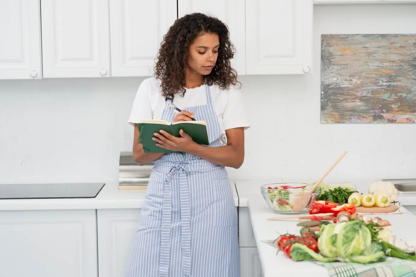 Lockige Frau hält ein Notizbuch und blickt auf Gemüse.